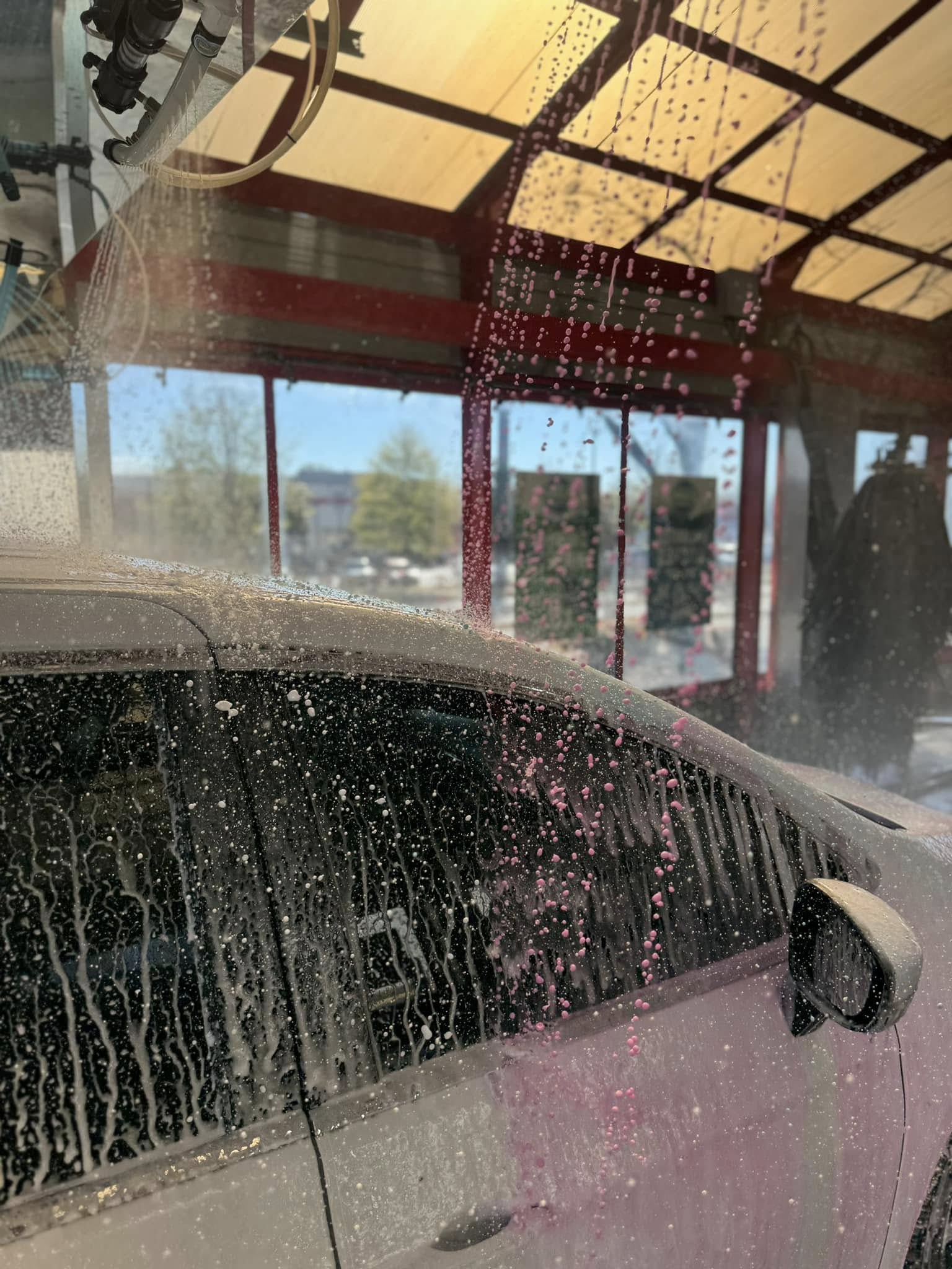 The pink triple foam wash being sprayed onto a vehicle during a car wash at Clean Car Wash and Detail in Fredericksburg, VA.